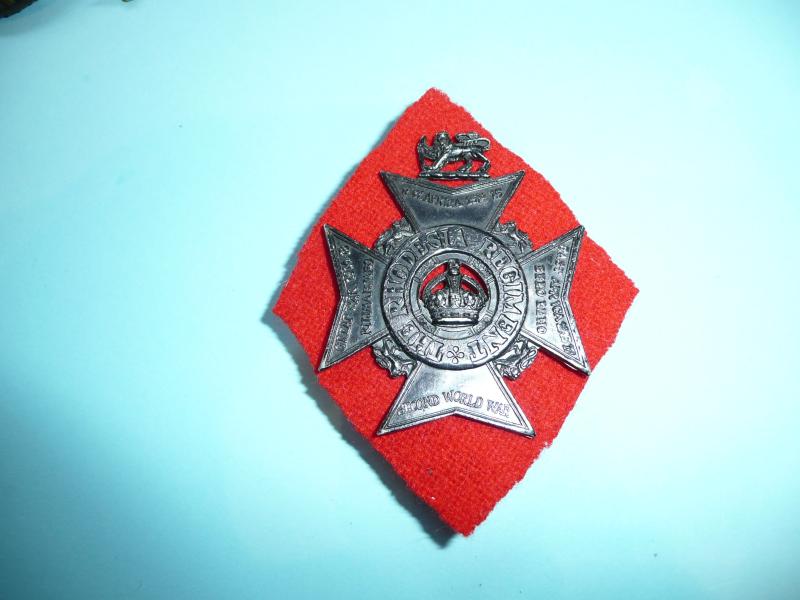 South Africa - The Rhodesia Regiment Blackened Anodised Aluminium AA Cap Badge with Red Felt Badge Backing